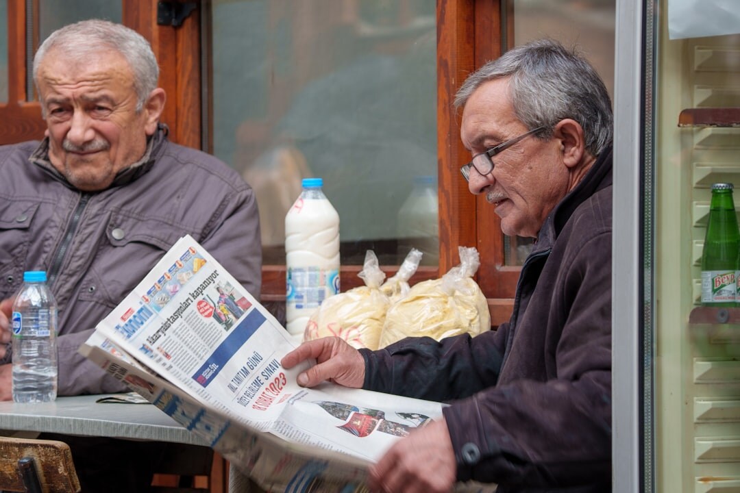 Seniors reading newspapers together at a community club table